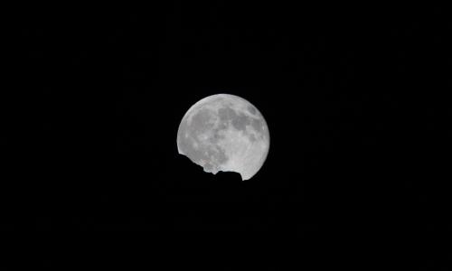 Pleine lune se levant derrière une crête, sur un ciel noir