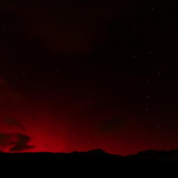 Faible lueur rouge sur l’horizon, sous un ciel nocturne encore sombre, au-dessus de collines noires